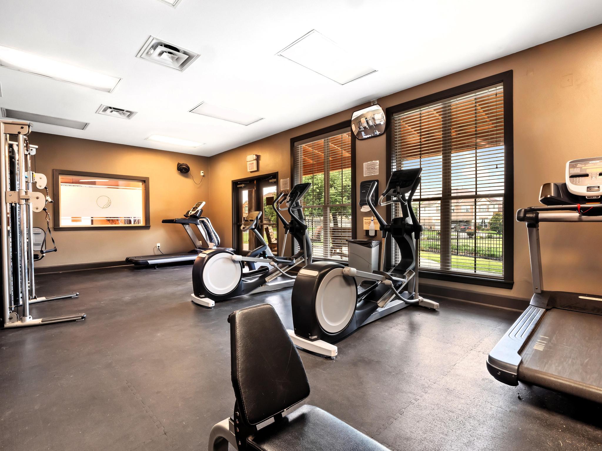 Blackhawk Amenity Center fitness room with cardio machines, windows, and warm interior finishes.