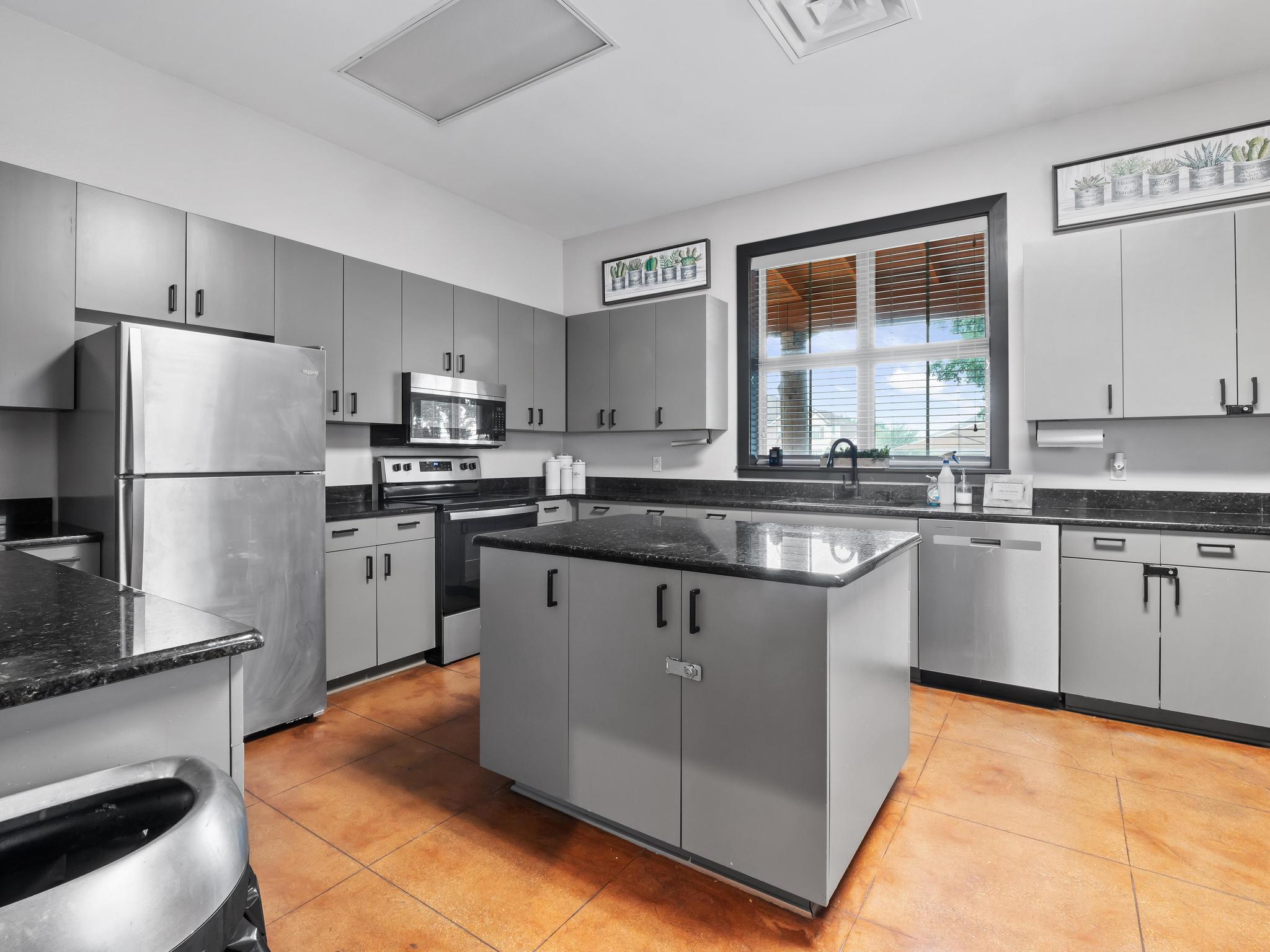 Blackhawk Amenity Center kitchen with cabinets, island, refrigerator, sink, and stove.