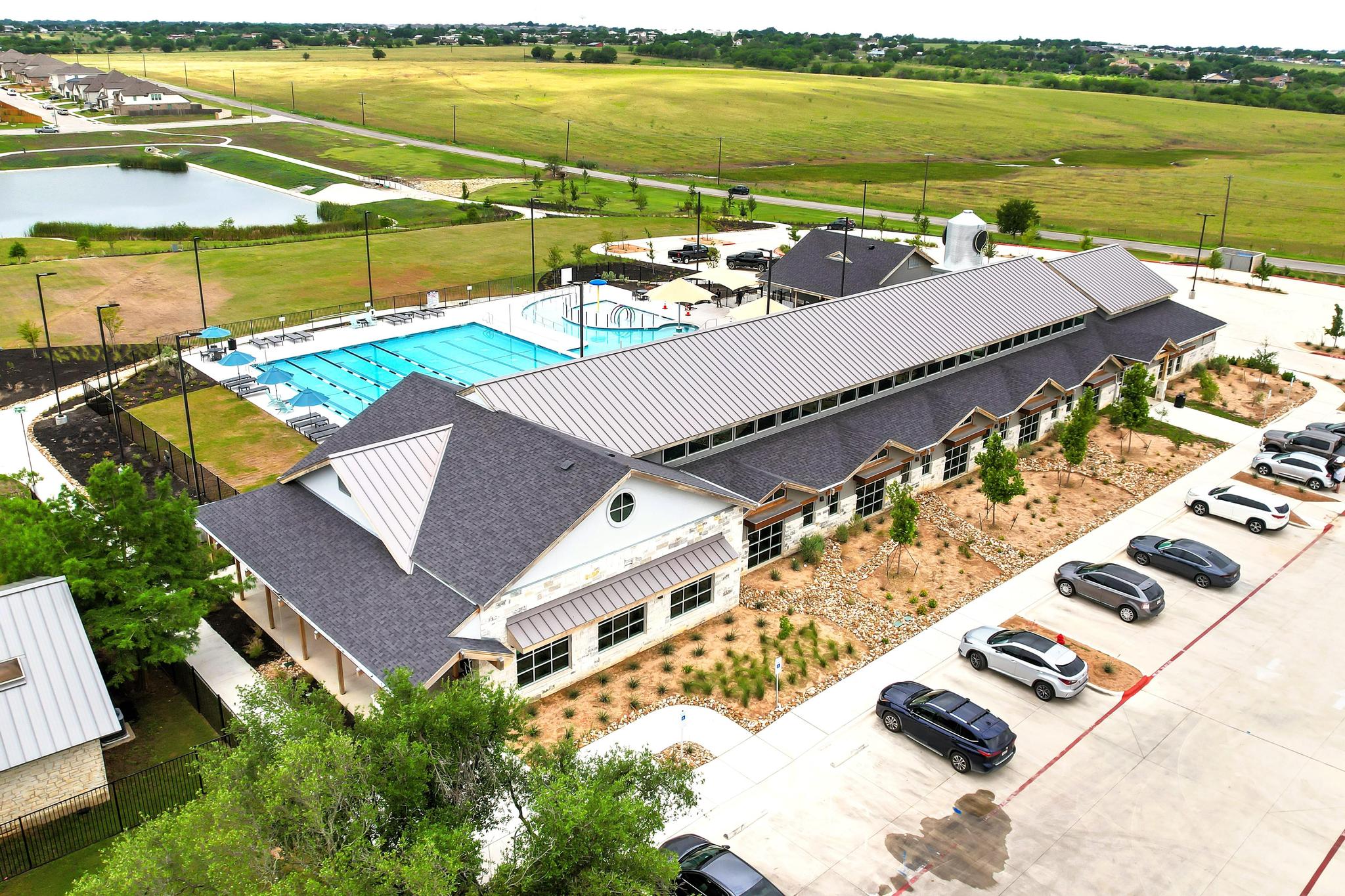 Aerial view of Carries Ranch Recreation Center with building, parking area, pool deck, and surrounding green space.
