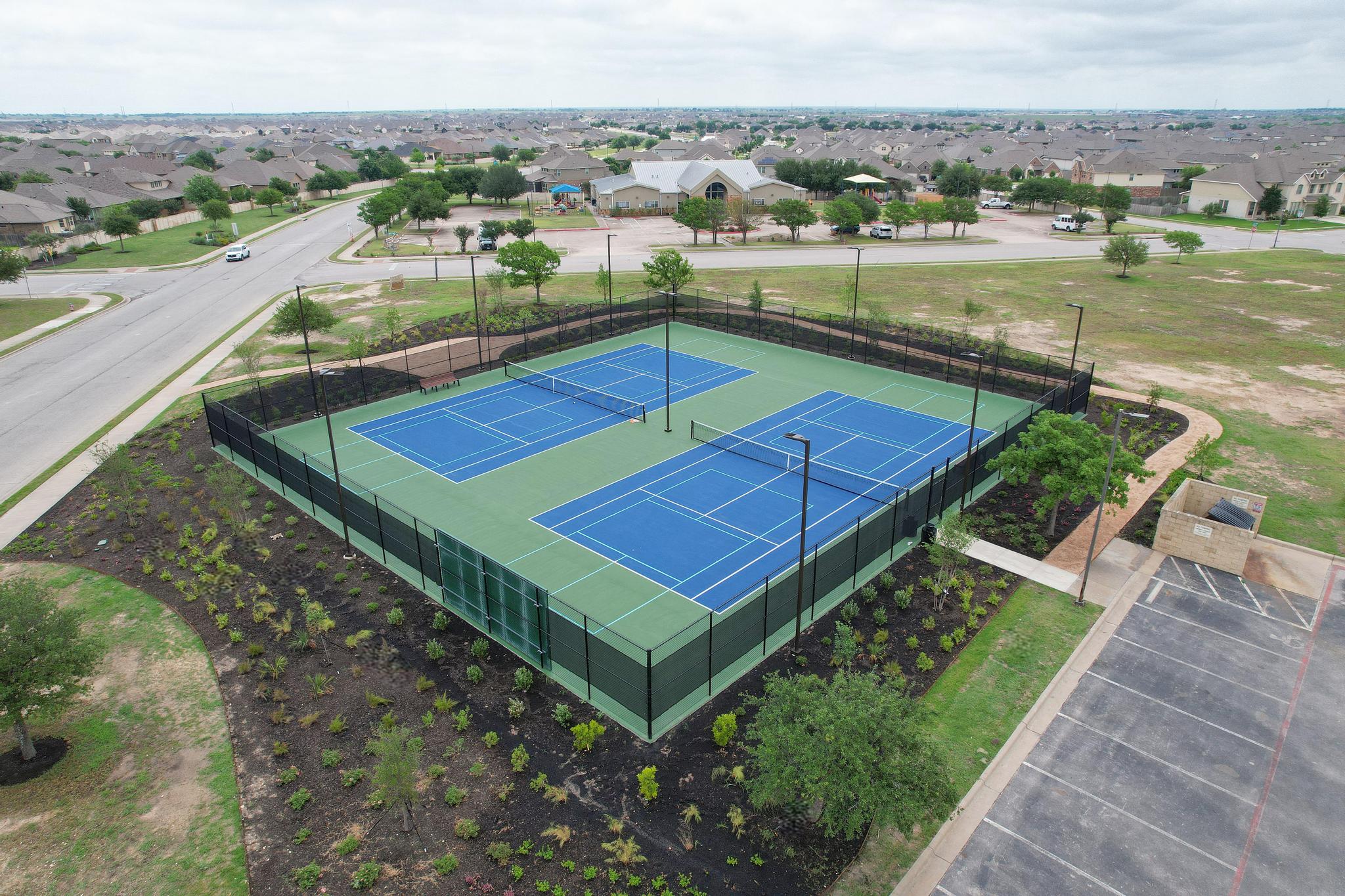 Aerial view of the Blackhawk sports courts with blue playing surfaces and surrounding fencing.